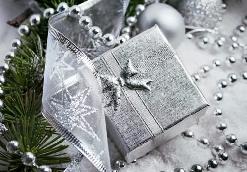 Silver gift box and christmas decoration in fake snow
