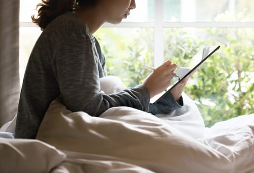 Working at morning, Worker women using stylus pen on digital tablet on bed