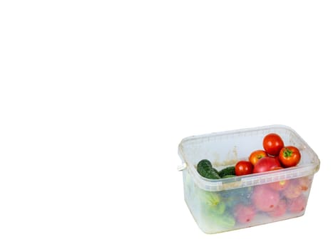 Vegetables, cucumbers and tomatoes in a plastic tray. Green cucumber. Red tomato. Harvesting vegetables. Plastic dishes. White background. Shop window. Agricultural business.