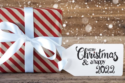 One Christmas Gift With Label With Egnlish Calligraphy Merry Christmas And A Happy 2022. Wrapping Paper With A Bow And Snowflakes