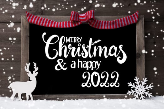 Chalkboard With English Calligraphy Merry Christmas And A Happy 2022. Decoration Like Deer And Bow. Gray Wooden Background With Snow And Snowflakes
