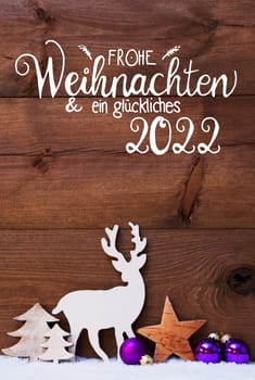 German Calligraphy Frohe Weihnachten Und Ein Glueckliches 2022 Means Merry Christmas And Happy 2022. Christmas Decoration With Tree, Deer And Purple Ball. Brown Wooden Background