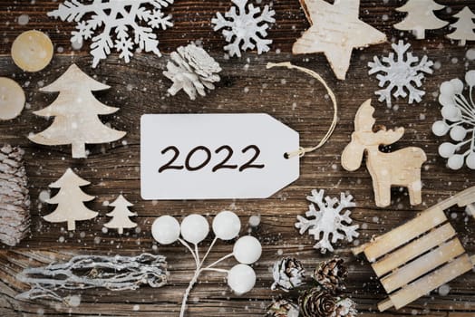 One White Label With Text 2022. Frame Of Christmas Decoration Like Tree, Sled, Star And Fir Cone. Wooden Background With Snowflakes