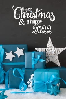 English Calligraphy Merry Christmas And A Happy 2022. Turquoise Gift With Bow And Decoration Like Star. Black Background With Snow