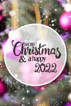 English Calligraphy Merry Christmas And Happy 2022. Christmas Tree With Blurry Pink Christmas Ball Ornament And Snowflakes