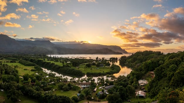 A vibrant aerial view of sunset clouds over the lush landscape of Hanalei Bay, framed by majestic mountains in Kauai, Hawaii.