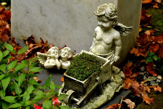 sweet angel figures on a grave in autumn with fallen leaves