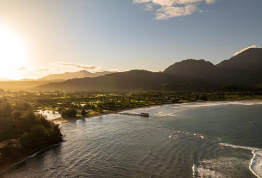 Aerial panoramic image at sunrise off the coast over Hanalei Bay and pier on Hawaiian island of Kauai