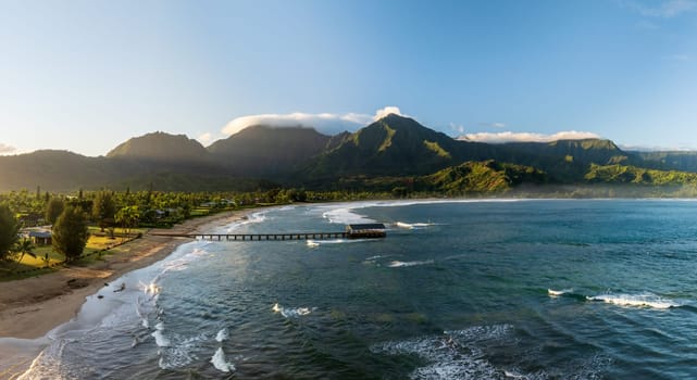 Aerial panoramic image at sunrise off the coast over Hanalei Bay and pier on Hawaiian island of Kauai
