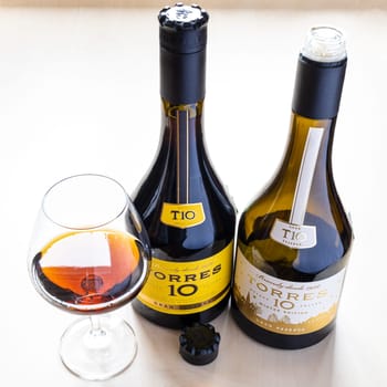 Moscow, Russia - October 16, 2021: two bottles with TORRES Gran Reserva 10 brandy and wineglass. Torres 10 Gran Reserva is the most popular Spanish brandy in world, it has been produced since 1946