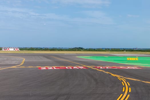 runway of airport with cloudy sky and print of wheels at the surface