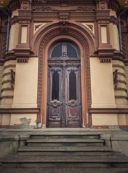 Vintage door and ornate facade details of an old historical building. Outdoors architecture elements. Rustic wooden gate. The main entrance doorway