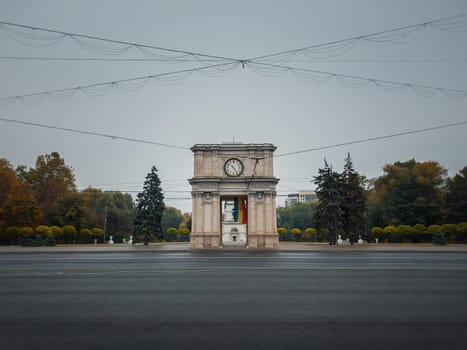 Triumphal Arch in Chisinau city, Moldova. Autumn season view from the street to the landmark in a rainy day..