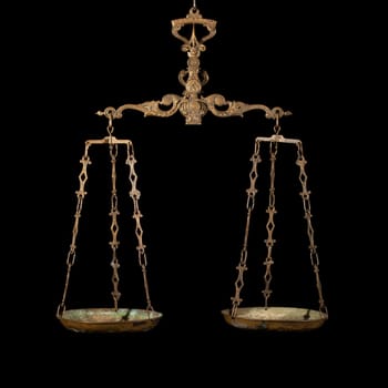 Antique rusty balance scale isolated on black background. Justice and making decision concept. Even odds, being in balance.