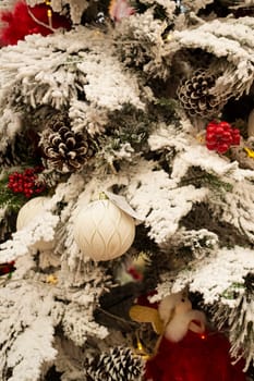 Christmas background with frozen spruce branch with snow. Happy new year pastel card. Red and white balls, vertical image