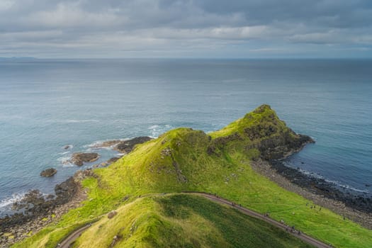 Tourists on the trail, visiting Giants Causeway, seen from top of the cliff, Wild Atlantic Way and UNESCO world heritage, located in Northern Ireland