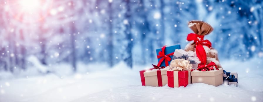 Pile of presents lying on the fresh snow in winter in forest. Gifts in wintertime outdoors. Christmas concept