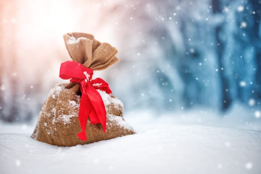 Present bag on the fresh snow in winter in forest. Gifts in wintertime outdoors. Christmas concept