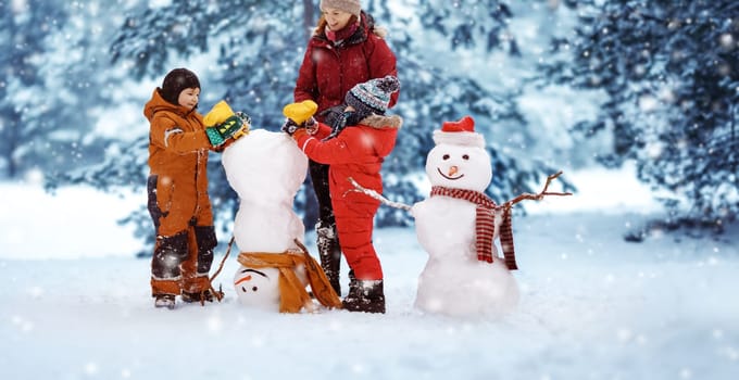 Mother and her children playing in the winter park. Woman and boys making a snowman.