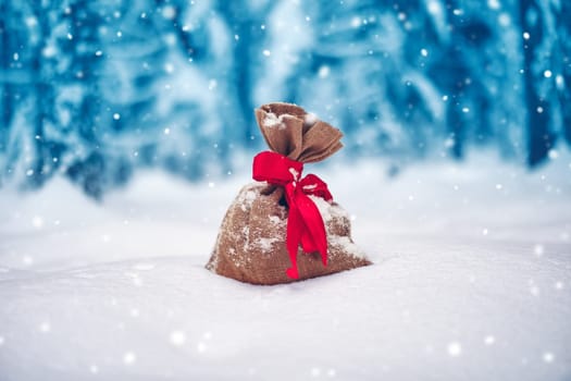 Present bag on the fresh snow in winter in forest. Gifts in wintertime outdoors. Christmas concept
