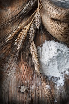 Wheat ears and flour sack on grunge wooden board