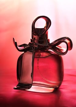 Bottle of perfume and pearls on purple silk