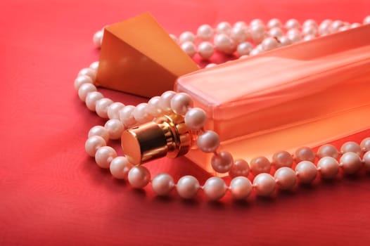 Bottle of perfume and pearls on purple silk