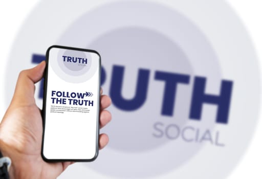 New York, USA, Oct 2021: hand holding a phone with the Truth Social mobile app on the screen and the logo blurred in the background. Truth Social is a social media platform launched by Donald Trump