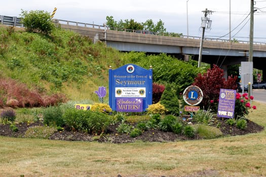 Seymour, CT, USA - May 28, 2021: Welcome to the Town of Seymour sign along with other local signs during the day. Town of Seymour welcome sign with flowers and foliage at the end of an exit ramp.