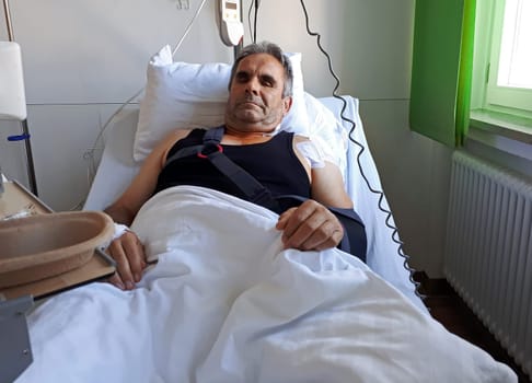 A man lies in a bed in the hospital after an operation