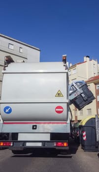 Trash truck collecting urban paper dumpster. Smart hydraulic system rise blue container automatically from side