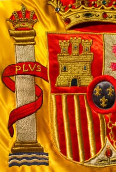 Coat of arms of Spain nation richly embroidered on its flag. Closeup