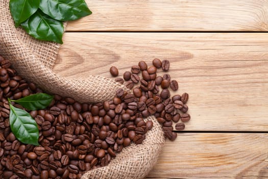 Coffee beans in the jute bag on wooden table. Top view