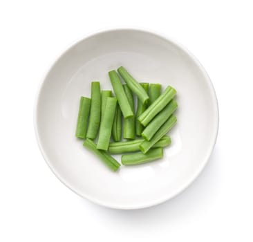 Chopped green beans in white bowl isolated over white background. Top view