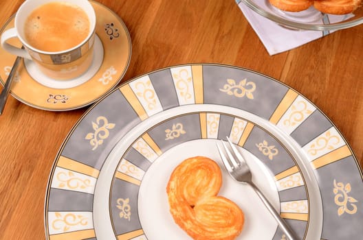 Puff pastry cookies with a cup of coffee on a woody table