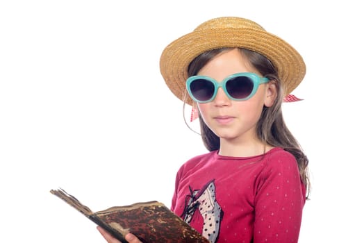 a little girl with sunglasses reads a book on white