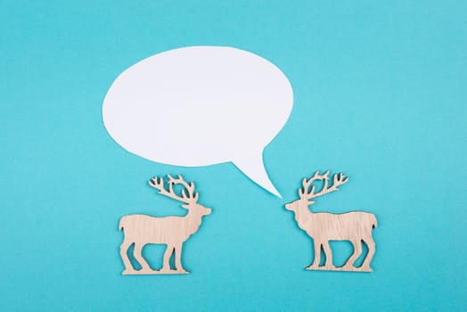 Two cute reindeers talking to each other, speech bubble with copy space, christmas greetings, blue colored background