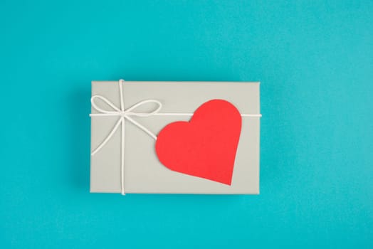 Gift box with a red heart, copy space for text, blue colored background, valintine day, birthday