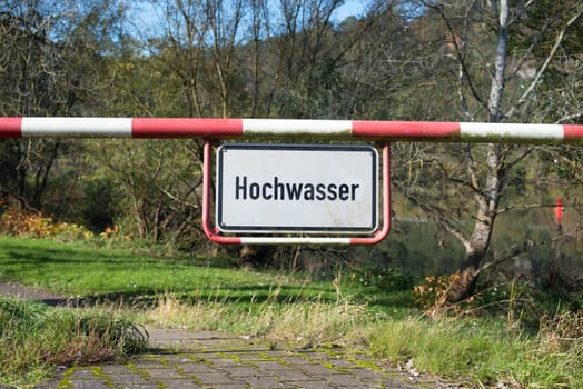 High water sign in german language, next to the river Moselle in Trier, warning for flood, climate change, enviromental issue