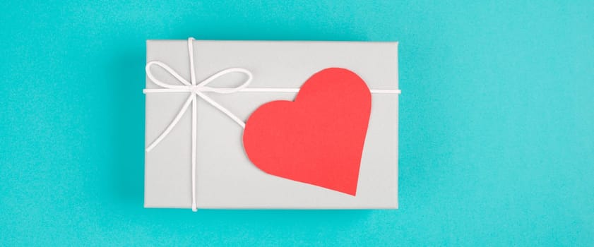 Gift box with a red heart, copy space for text, blue colored background, valintine day, birthday