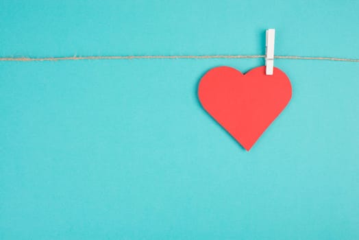 A heart hanging on a clothing line, blue colored background, empty copy space, symbol of love, valintine greeting card