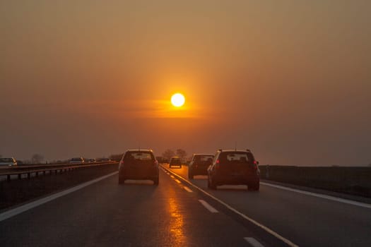 traffic at the european highway with cars and romantic sunset in front