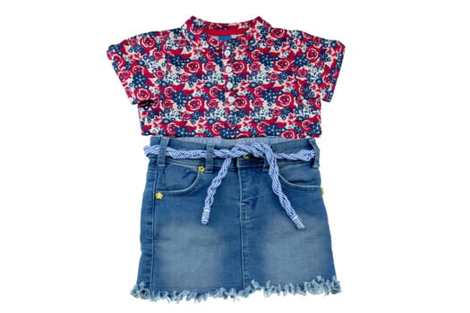 Jeans skirt. Close-up of a sexy short blue jeans skirt with blue white linen twine and a fashionable little girl shirt with floral print isolated on a white background. Denim fashion for girls.