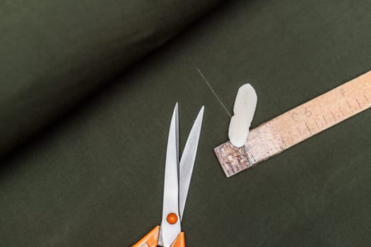tailor marks up textile using soap and wooden ruler on pattern cutting.