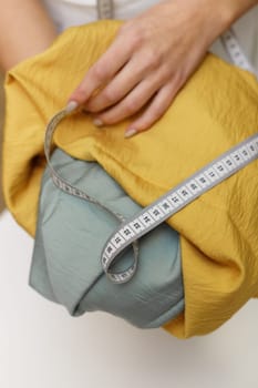 Close-up of the tailor hands with fabric and measuring tape