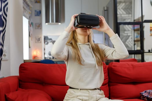 happy young woman with virtual reality headset or 3d glasses playing game at home and touching something invisible.