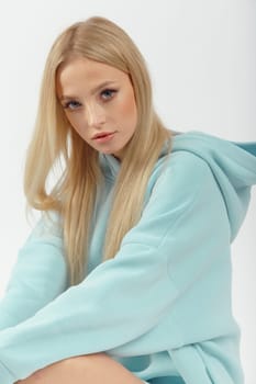 Young pretty woman wearing turquoise hoodie on white background. Casual women sport look