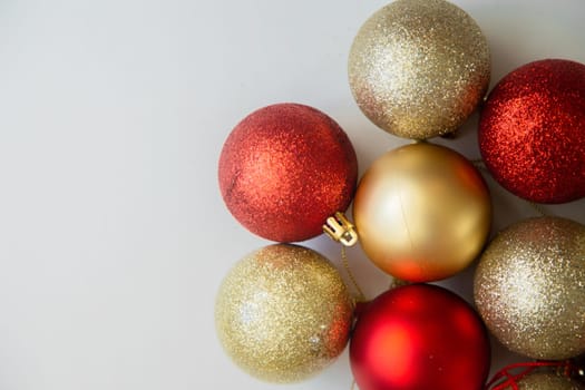 Golden and red Christmas balls with and without sequins lie on a white background. High quality photo