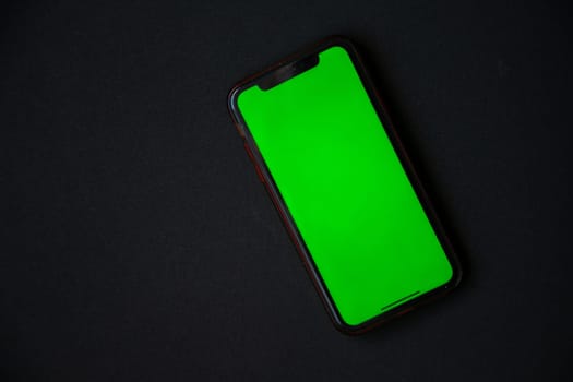 The phone with a green screen is on a black background. . High quality photo