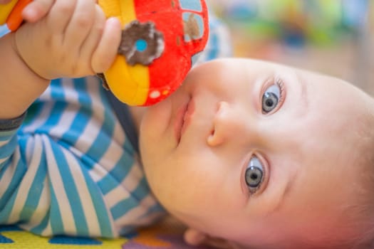 The little kid smiles and hugs the rattle machine to himself. High quality photo